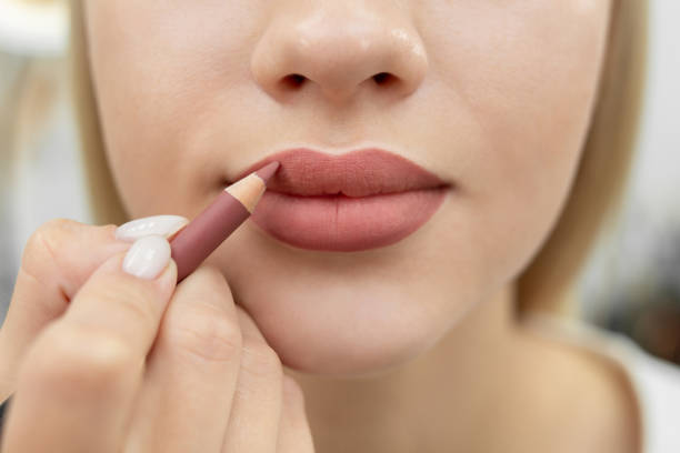 maquillaje de labios. primer plano de una cosmetóloga pintándose los labios con un lápiz después del maquillaje permanente. - lip liner fotografías e imágenes de stock