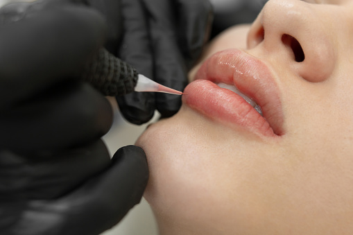 Primer plano del procedimiento de maquillaje permanente. Maquillaje de labios en el salón del cosmetólogo. photo