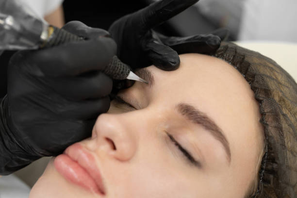 istock Concept of microblading eyebrows. The cosmetologist performs the procedure of permanent makeup of the eyebrows in close-up. 1355816958