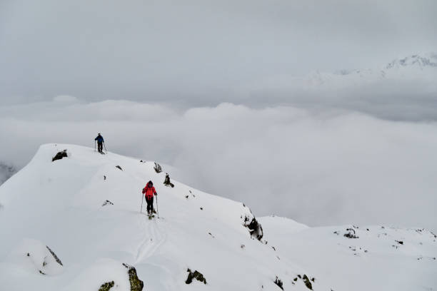 istock Friends backcountry ski down snowy mountain ridge 1355817927