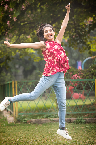 Carefree woman having fun and jumping in air at park