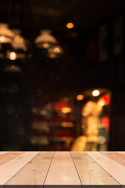 istock Empty wooden table top with lights bokeh on blur restaurant background. 1355819252