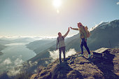 Personal perspective of Two hikers celebrating on mountain top with a high five