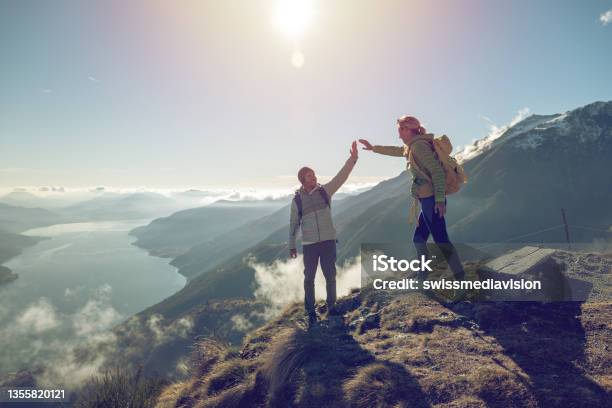 Personal Perspective Of Two Hikers Celebrating On Mountain Top With A High Five Stock Photo - Download Image Now