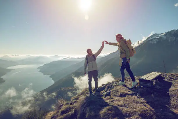 Two hikers celebrating on mountain trail with a high five. Shot in Switzerland, Springtime.