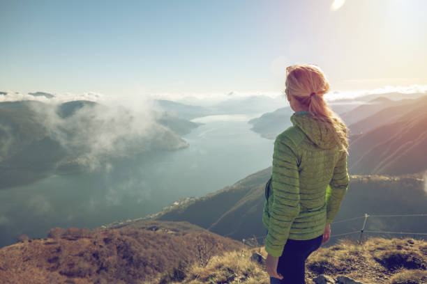 istock Woman hiking on mountain top, lake view 1355820126