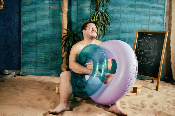 istock Funny fat man is resting on the beach. 1355820746