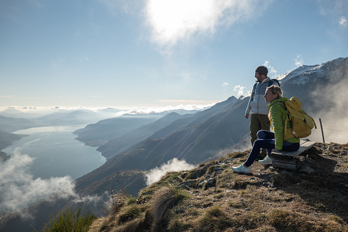 Young couple hiking in Switzerland looking at breathtaking lake view 
People travel and enjoying outdoors activity concept.