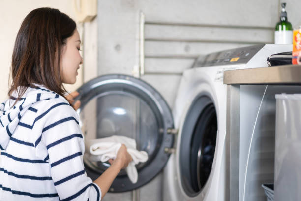 A woman using a drum-type washing machine A woman using a drum-type washing machine laundromat laundry residential structure cleaning stock pictures, royalty-free photos & images