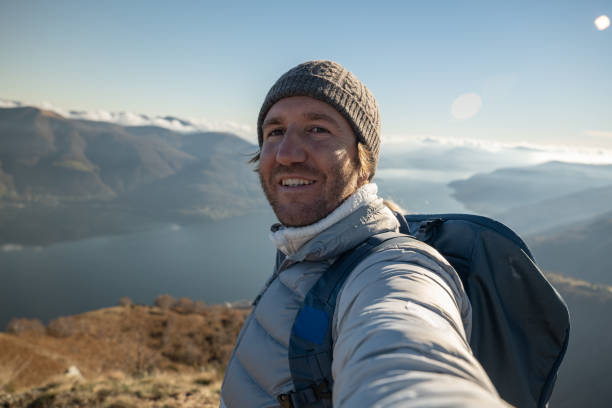 istock Cheerful young man taking a selfie portrait on mountain top 1355823957