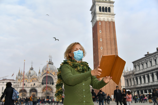 A senior white woman wearing a protective mask in Venice during Covid-19, Italy, Europe.