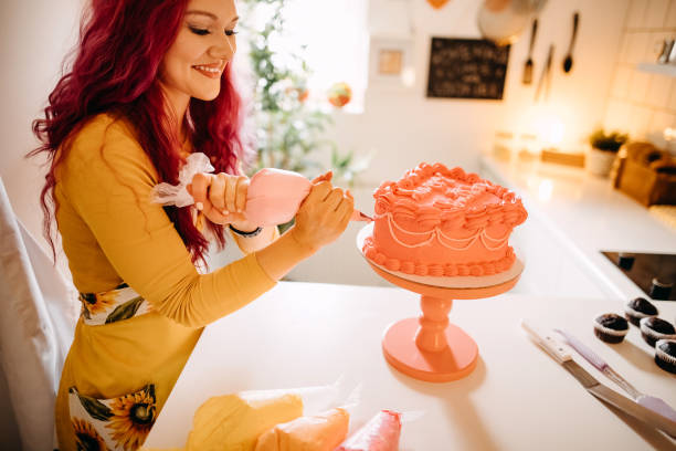 Woman in her kitchen decorates a birthday cake she made herself