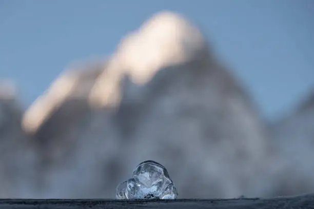 a small cube of ice in front of a large mountain in upper Austria.