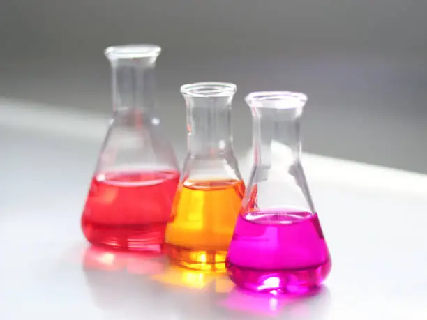 Photo of The Erlenmeyer or Conical flask on bench laboratory, with colorful solvent solution from titration experiment. Parameter of acidity and alkalinity, acid-base analysis compounding in wastewater sample.