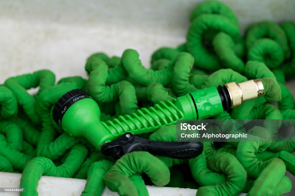 Flexible hose pipe Close up of a flexible concertina type hosepipe in an English garden. Garden Hose Stock Photo