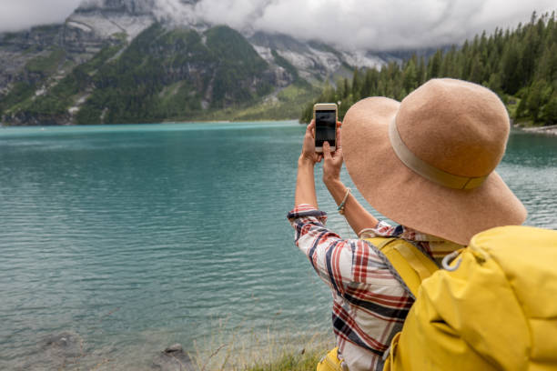 Young woman takes photo while hiking around beautiful alpine lake Happy hiker takes photo of the lake and mountains on background.
People travel outdoor activities in Summer lake oeschinensee stock pictures, royalty-free photos & images