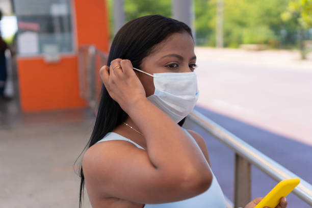 istock woman wearing face mask using phone in bus station. 1355830016