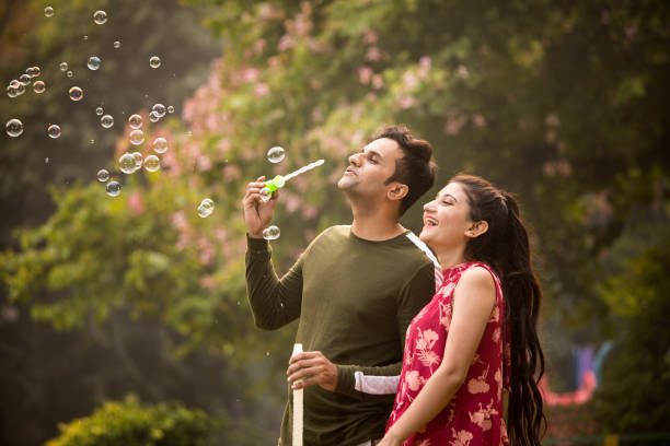 istock Young couple blowing bubbles at park 1355834332