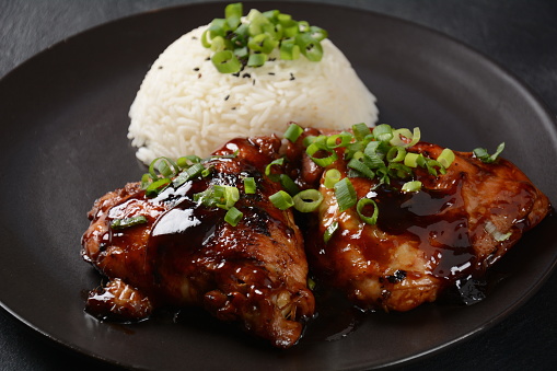 Chicken thighs marinated and cooked in adobo sauce. National filipino dish. Adobo with rice close-up on a plate.