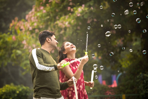 istock Young couple blowing bubbles at park 1355834387