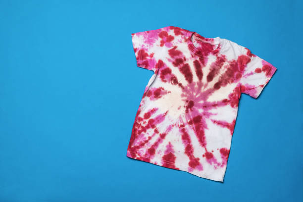 istock Two brushes and a tie dye T-shirt on a blue background. Flat lay. 1355834931