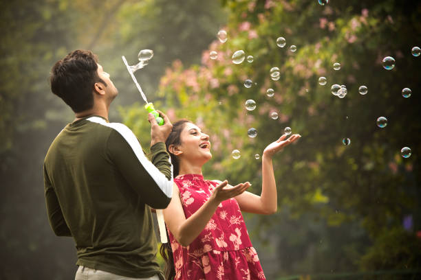 istock Young couple blowing bubbles at park 1355835456