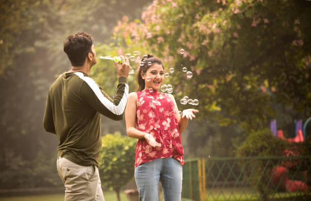 istock Young couple blowing bubbles at park 1355835483