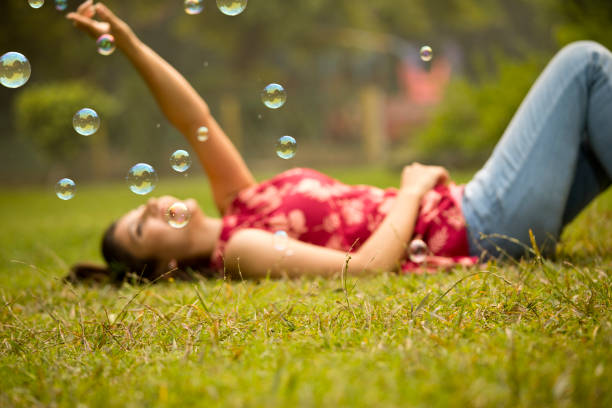 istock Woman lying on grass and touching bubbles at park 1355835548