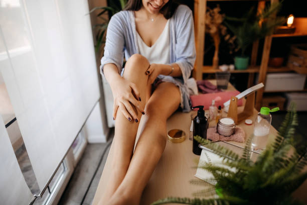 beautiful woman nurtures her legs - moisturizer women cosmetics body imagens e fotografias de stock