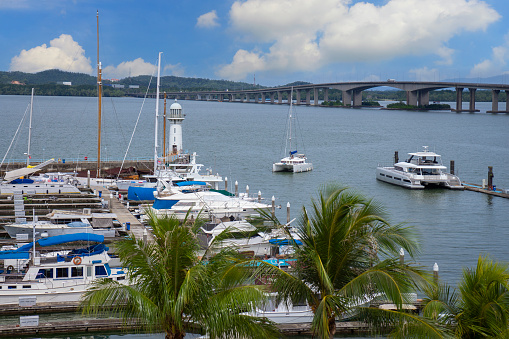 Vessels moored before the Raffles Marina Lighthouse, with the Tuas Second Link causeway that links Singapore and Malaysia in the background.