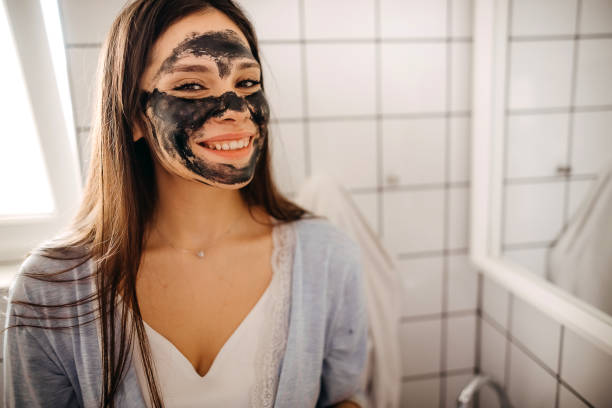 istock Woman applying black nourishing mask on face 1355836559