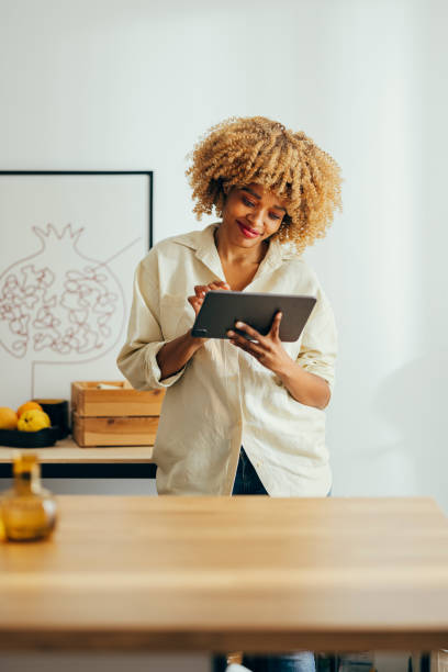 istock Beautiful Cheerful Woman Standing and Using her Tablet 1355840302