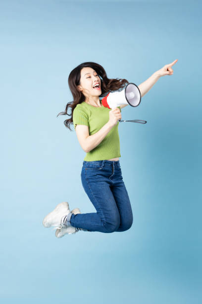 portrait of beautiful young asian girl jumping up, isolated on blue background - filipino ethnicity audio imagens e fotografias de stock