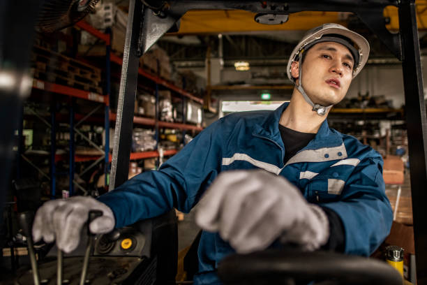 Asian male factory worker operating a forklift. stock photo