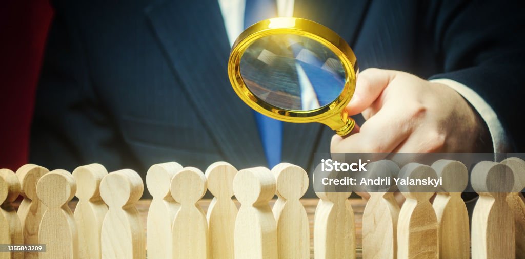 Businessman is studying a crowd of people with a magnifying glass. Hr search candidates for work, staff recruiting. Society, demographic. Market and customers research. Citizens electorate. Sociology Market - Retail Space Stock Photo