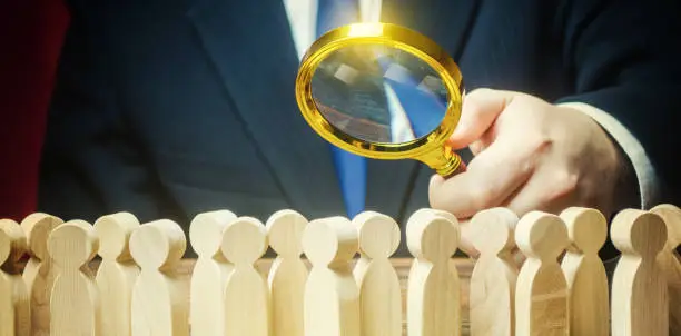 Photo of Businessman is studying a crowd of people with a magnifying glass. Hr search candidates for work, staff recruiting. Society, demographic. Market and customers research. Citizens electorate. Sociology