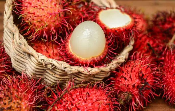 Photo of Red Rambutan fruit in basket with inner flesh visible