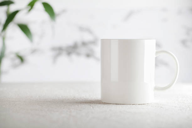 istock Mug mockup with green plant on white background. Copy space selective focus. Blank cup for your design. space for your text, image and logo. 1355846434