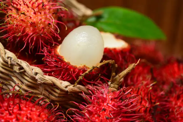 Photo of Red Rambutan fruit in basket with inner flesh visible