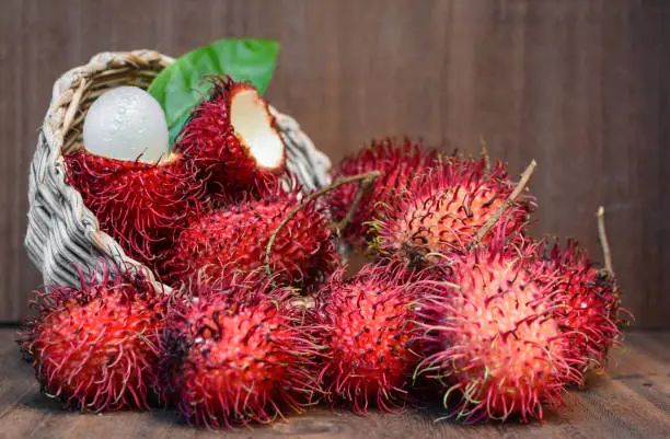 Photo of Red Rambutan fruit in basket with inner flesh visible