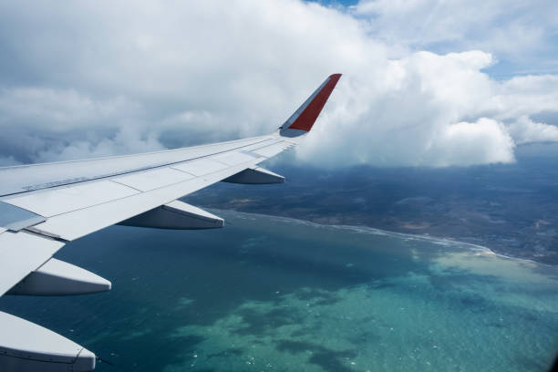 Classic image through aircraft window onto wing. Flight view over sea in cloudy weather.