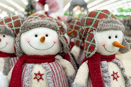 Smiling faces of snowman's dolls wearing winter hats and scarfs in the store on the eve of Christmas and New Year