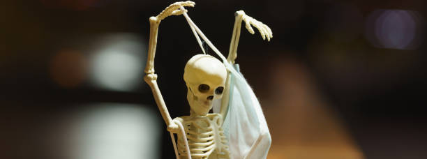 istock skeleton toy with surgical mask sitting on a bench at autumn night 1355852485