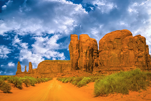 Colorful vivid desert landscape of Monument Valley in Arizona, USA. Crumbling sandstone cliffs and blue sky. Popular tourist attraction in the American Wild West. Navajo tribal park