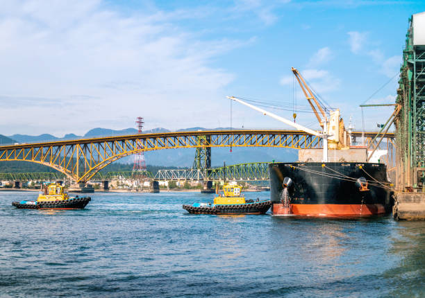 two tug boats approaching a docked tanker at a port terminal of vancouver - vancouver harbor imagens e fotografias de stock