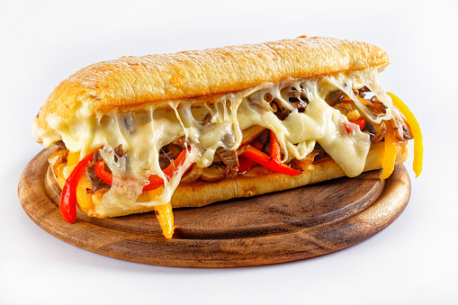philadelphia cheese steak sandwich with roasted beef, pepper, caramelized onion, mushrooms and melted cheese on a wooden board
