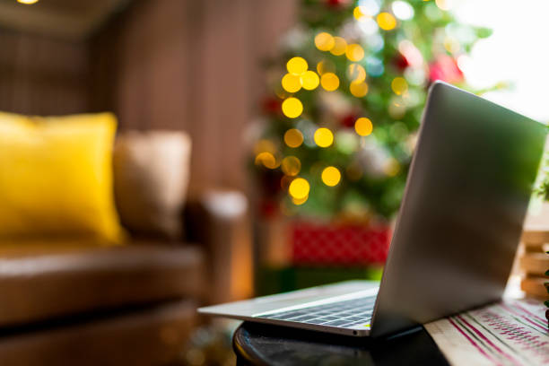 working on christmas eve holidays,laptop on table with christmas tree with light decorating bokeh at condominuam apartment  working hard on weekend holidays ideas concept