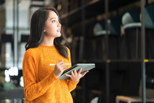 confianza inteligente mujer asiática emprendedora pequeña empresa propietaria empresaria mujer de negocios usar tela casual inteligente sonrisa mano usar tableta woking inventario verificación en la sala de exposición oficina fondo diurno - warehouse manager place of work portrait fotografías e imágenes de stock