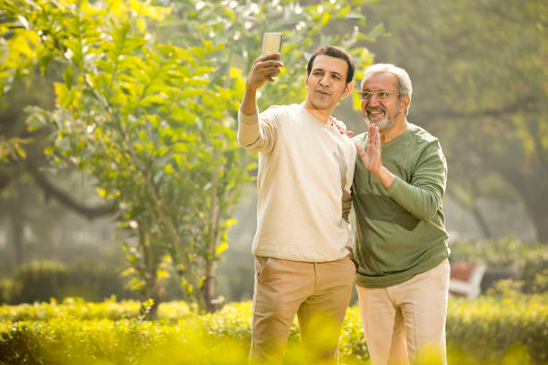 istock Senior man and son using mobile phone at park 1355859468