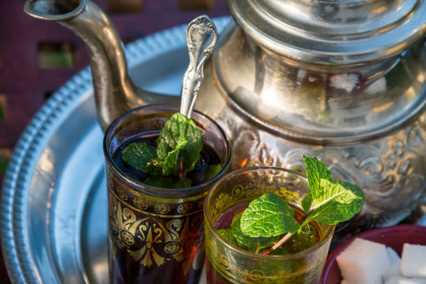 Moroccan mint tea Glasses with tea and traditional Moroccan teapot mint tea stock pictures, royalty-free photos & images